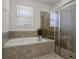 Bright bathroom featuring a bathtub and walk-in shower with glass doors and neutral tiling at 7527 Marker Ave, Kissimmee, FL 34747