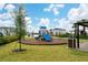 Charming community playground with modern play structure, lush grass, and a comfortable, shaded seating area for families at 8967 Chipping Square Ln, Davenport, FL 33896