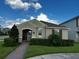 A charming single-story home with a well-manicured lawn, lush greenery, and a brick walkway to the entrance at 9318 Mclaren Aly, Winter Garden, FL 34787