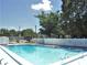 Community pool with a fence, mature trees, and bright blue water at 1024 Spring Meadow Dr, Kissimmee, FL 34741