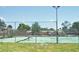 Outdoor community tennis court with green surface and high surrounding fence at 1024 Spring Meadow Dr, Kissimmee, FL 34741