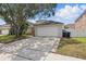 View of the home’s driveway, two-car garage, landscaping, and exterior at 14006 Yellow Wood Cir, Orlando, FL 32828