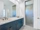 Bathroom featuring dual vanities, a large mirror, and a walk-in shower, designed for functionality and style at 235 Hampton Loop, Davenport, FL 33837