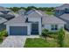 Exterior view of a modern home with a gray garage door, paver driveway, and lush landscaping at 235 Hampton Loop, Davenport, FL 33837