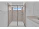 Bathroom featuring tiled shower stall with glass enclosure, window, rainfall shower head and shelving niche at 2845 Pierr St, Davenport, FL 33837