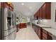 Stainless steel refrigerator complements granite countertops and cherry wood cabinetry at 3641 Bristol Cove Ln, St Cloud, FL 34772