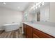 Bathroom with a soaking tub, wood-look floors, wood cabinets and white quartz countertops at 3720 Edsel Ave, St Cloud, FL 34772