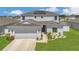 Two-story home featuring a two-car garage, well-manicured lawn, and solar panels on the roof at 374 Pine Tree Bridge Trl, St Cloud, FL 34772