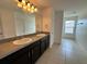 Bathroom featuring dual sinks, black cabinets, and large mirror at 4804 Marcos Cir, Kissimmee, FL 34758