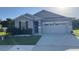 Inviting single-Gathering home featuring stone veneer accents, a two car garage, and green lawn at 5306 Meadow Song Dr, Okahumpka, FL 34762