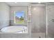 Modern bathroom showcasing a large soaking tub and a separate tiled shower with a glass door at 563 Viceroy Ct, Kissimmee, FL 34758
