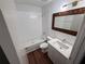 Bathroom features white tiled shower, white vanity, decorative mirror and wood-look floors at 709 Orchid Dr, Davenport, FL 33897