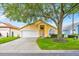 Charming single-Gathering home featuring an attached two-car garage and a well-manicured front lawn with mature tree at 1113 Casterton Cir, Davenport, FL 33897