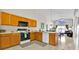 Well-lit kitchen with wooden cabinets, modern appliances, a breakfast bar, and an adjacent living space at 1113 Casterton Cir, Davenport, FL 33897