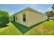 Back exterior view of a yellow home with a well maintained lawn, sliding glass doors, and mature landscaping at 1258 Donalds Pl, The Villages, FL 32162