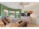 Bedroom with green walls, bay windows, ceiling fan, and a TV on a dresser at 1258 Donalds Pl, The Villages, FL 32162