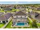 Aerial view of the backyard featuring a screened-in pool and spa, nestled among neighboring homes at 152 Whirlaway Dr, Davenport, FL 33837