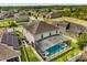 Aerial view of property with screened pool, lush backyard, and solar panels on the roof at 152 Whirlaway Dr, Davenport, FL 33837