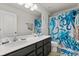 Bathroom with double vanity, large mirror, and a shower with patterned curtain at 152 Whirlaway Dr, Davenport, FL 33837