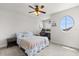 Comfortable bedroom features a ceiling fan, carpet flooring, and a unique, eye-catching round window at 152 Whirlaway Dr, Davenport, FL 33837