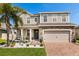 Beautiful two-story home with a stone accent, a lush lawn, and a brick driveway for added curb appeal at 152 Whirlaway Dr, Davenport, FL 33837