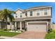 Two-story home showcases a two-car garage, brick driveway, and beautifully landscaped front yard at 152 Whirlaway Dr, Davenport, FL 33837