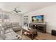 Bright living room featuring a gray leather couch, wood floors, ceiling fan and a TV on the wall at 152 Whirlaway Dr, Davenport, FL 33837