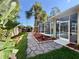 The serene backyard featuring a stone walkway and tropical foliage leads to a screened pool area at 1784 Sparkling Water Cir, Ocoee, FL 34761