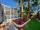 Backyard with palm trees and colorful plantings that lead to a screened in pool at 1784 Sparkling Water Cir, Ocoee, FL 34761