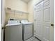 Functional laundry room with washer, dryer, shelving, and a door, providing convenience and organization at 1784 Sparkling Water Cir, Ocoee, FL 34761