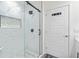 Modern bathroom with a glass shower, marble tiles and a white door with hooks behind it at 185 E Warren Ave, Longwood, FL 32750