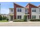 A modern townhouse with gray stucco and red siding, featuring a well-manicured lawn and inviting entrance at 185 E Warren Ave, Longwood, FL 32750