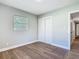 This bedroom features wood flooring, a closet, a window, and a connecting doorway at 220 Hillside Dr, Lakeland, FL 33803