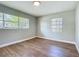The light-filled bedroom is painted a neutral gray, with hardwood floors, and two windows at 220 Hillside Dr, Lakeland, FL 33803