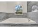 Bathroom showcasing a spa-like tub with gray accent tiles and a curved window at 242 Anson Dr, Kissimmee, FL 34758