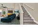 Bright living room with comfortable blue sofa, staircase, and dark ceiling fan at 242 Anson Dr, Kissimmee, FL 34758