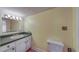 Bathroom vanity featuring a dark green countertop and vintage lighting fixture and toilet at 2652 N Woodland Blvd, Deland, FL 32720
