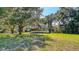 A two-story home with a wrap-around porch is surrounded by large, mature trees and a green lawn at 2652 N Woodland Blvd, Deland, FL 32720