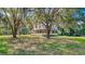 A picturesque two-story home with a wrap-around porch is nestled among mature trees on a lush lawn at 2652 N Woodland Blvd, Deland, FL 32720