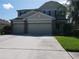 Two-story home with a large driveway, two-car garage, and well-maintained lawn at 3003 Cobham Rd, Kissimmee, FL 34758