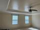 Bright main bedroom featuring tray ceilings, a ceiling fan, and large windows at 3003 Cobham Rd, Kissimmee, FL 34758