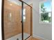 Modern shower features sleek tile, glass enclosure, and natural light from the window for a spa-like feel at 3629 Sublett Loop, Tavares, FL 32778