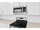 Close-up of the new kitchen's stainless steel microwave and electric range with bright white cabinetry at 4071 Bannock Ave, Tavares, FL 32778