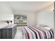 Bright bedroom with a window view, tile floor, red/gray bedding, and a dark dresser at 42 Chip Ct, Kissimmee, FL 34759