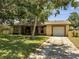 Single-story home with attached garage, featuring well-maintained front yard and mature trees at 42 Chip Ct, Kissimmee, FL 34759