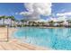 Community pool surrounded by palm trees and lounge chairs on a sunny day at 501 Pheasant Dr, Haines City, FL 33844