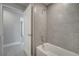 Well-lit bathroom with tub, shower, and modern gray tile walls at 557 Viceroy Ct, Kissimmee, FL 34758