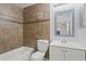 Bathroom featuring tile surround tub, toilet, and white vanity with blue framed mirror at 6548 Swissco Dr # 61, Orlando, FL 32822