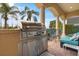 Covered outdoor grill with stainless steel appliances and countertop in a patio with ample seating and palm trees at 781 Golden Bear Dr, Kissimmee, FL 34747