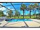 Inviting screened-in pool and spa with tropical landscaping and clear blue skies at 847 Orista Dr, Davenport, FL 33897